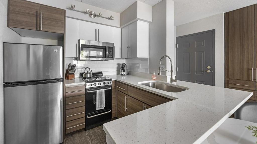 a kitchen with a stainless steel refrigerator and a sink at Landing Modern Apartment with Amazing Amenities (ID3931X23) in Phoenix