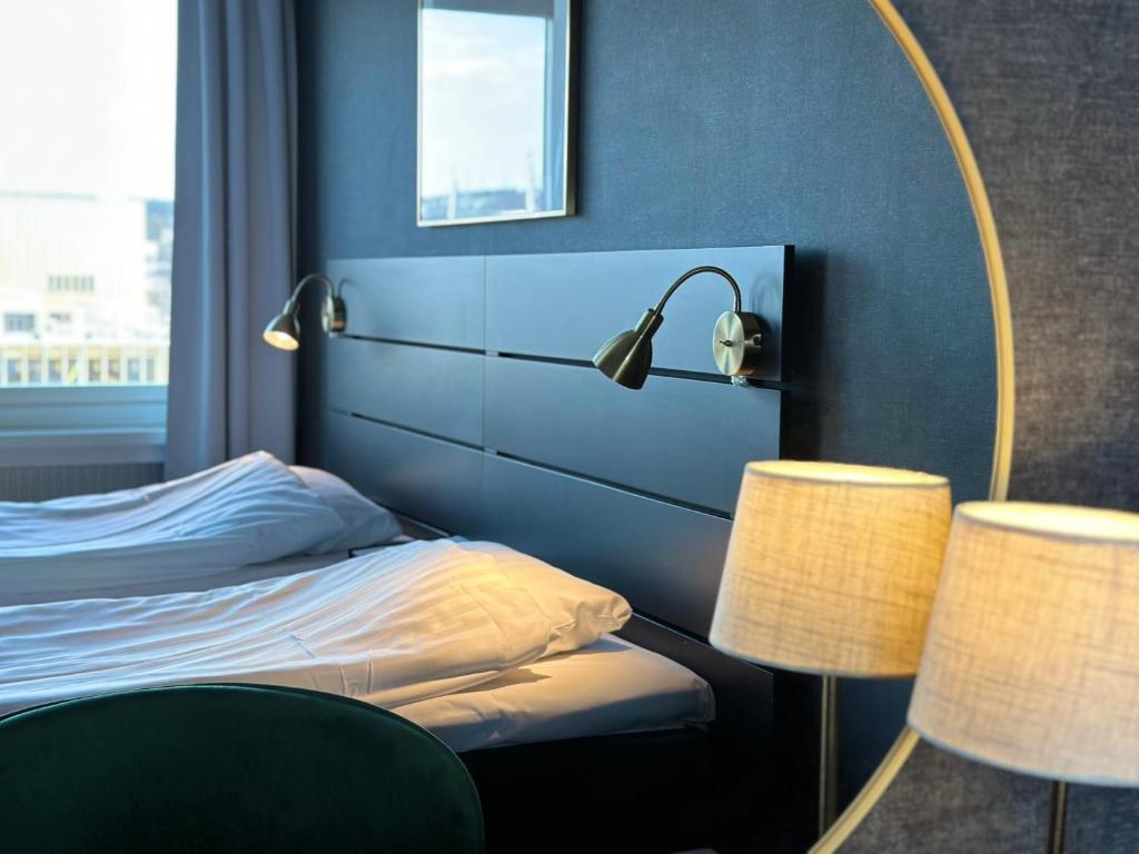 ein Schlafzimmer mit einem Bett mit einem Spiegel und 2 Lampen in der Unterkunft Hotel Victoria in Skellefteå