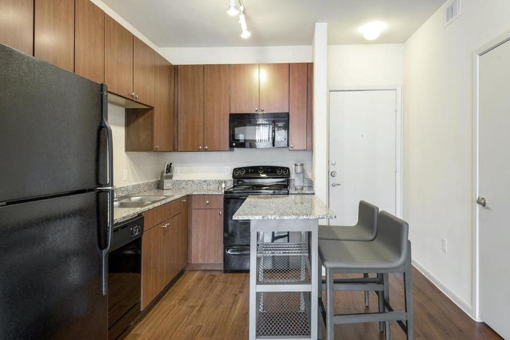 - une cuisine avec des placards en bois et un réfrigérateur noir dans l'établissement Landing Modern Apartment with Amazing Amenities (ID1800X49), à Birmingham