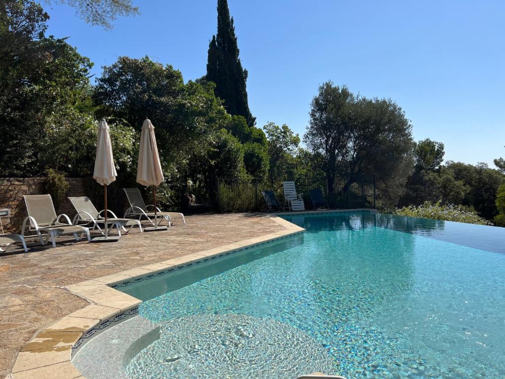 - une piscine avec des chaises longues et des parasols dans l'établissement La Villa des Pins à Benat, à Bormes-les-Mimosas