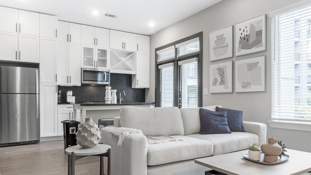 a living room with a white couch and a kitchen at Landing Modern Apartment with Amazing Amenities (ID1208X667) in Decatur