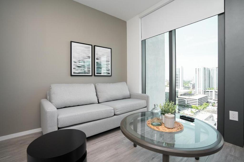 uma sala de estar com um sofá e uma mesa de vidro em Landing Modern Apartment with Amazing Amenities (ID1398X788) em Fort Lauderdale