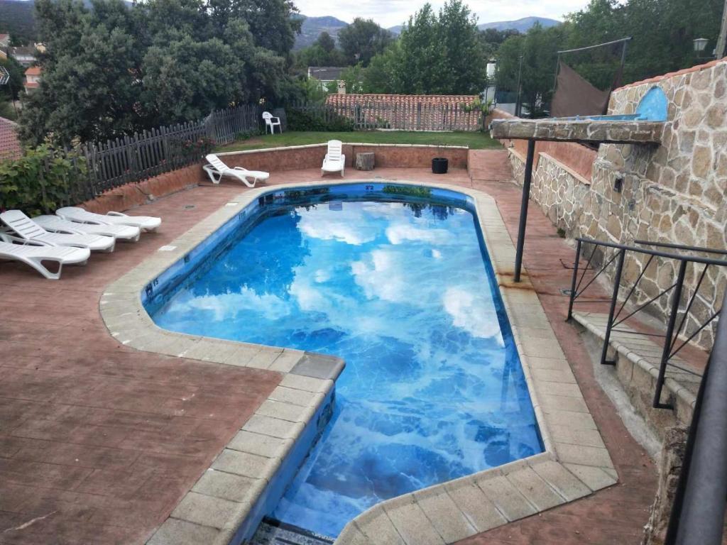 a large pool with blue water in a yard at Chalet Rural en Navaluenga in Navaluenga