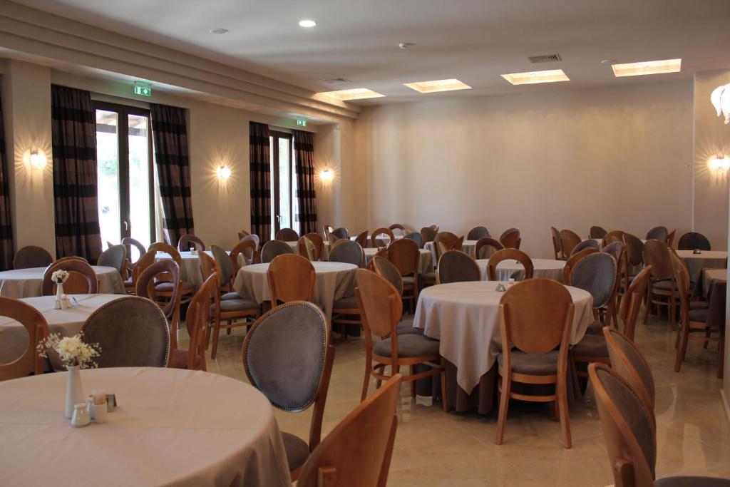 a room full of tables and chairs with white table cloth at Grand Meteora Hotel in Kalabaka
