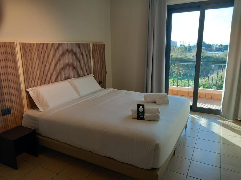 1 dormitorio con 1 cama blanca grande y ventana en B&B HOTEL Pomezia Cortese, en Pomezia