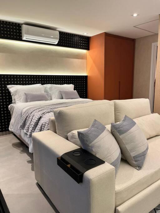 ein Schlafzimmer mit einem Bett und einem Sofa mit Kissen in der Unterkunft Lindo estúdio em Marilia - ao lado do Ibis in Marília