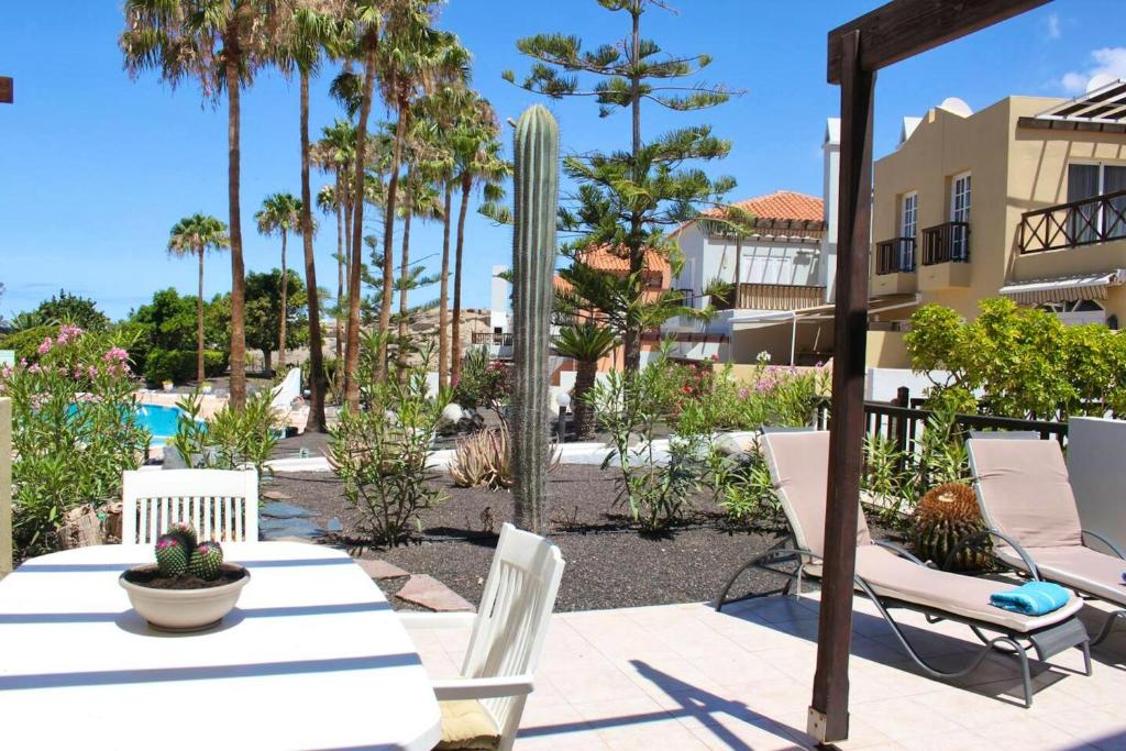 a patio with a table and chairs and palm trees at 2 bedrooms appartement with shared pool terrace and wifi at Costa Adeje in Santa Cruz de Tenerife