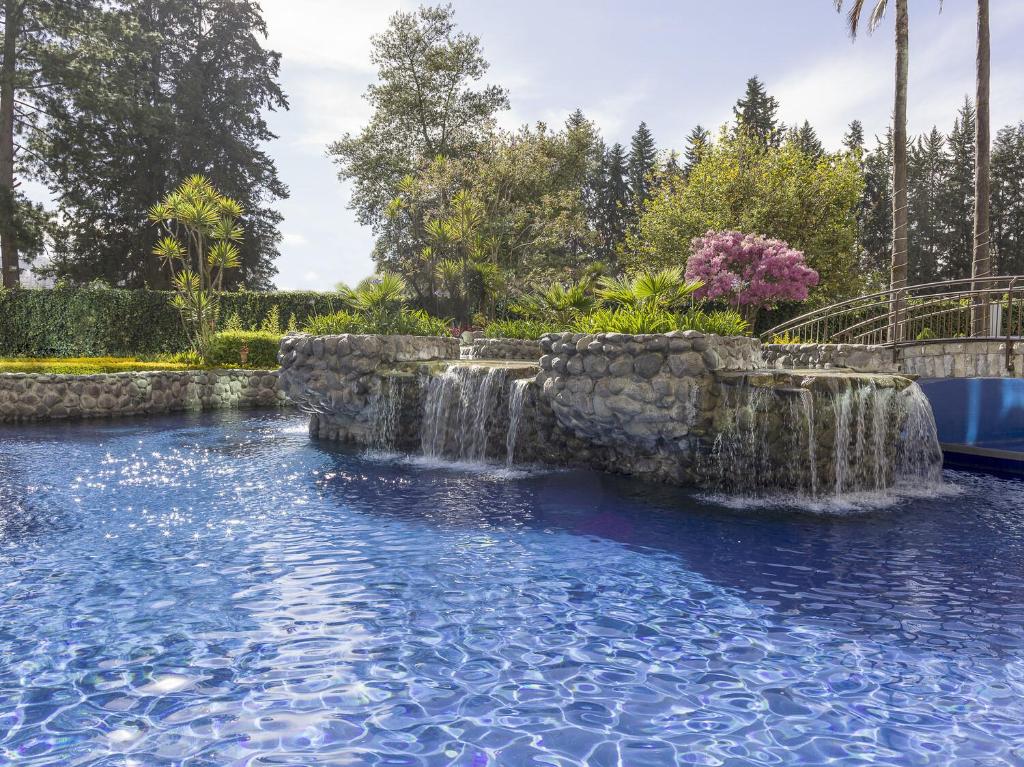 a swimming pool with a waterfall in a yard at Aparta Hotel Torres de Suites in Quito