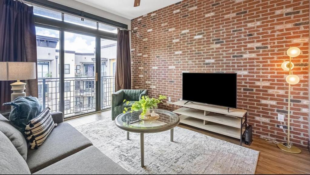 a living room with a brick wall and a flat screen tv at Landing Modern Apartment with Amazing Amenities (ID1278) in St Petersburg