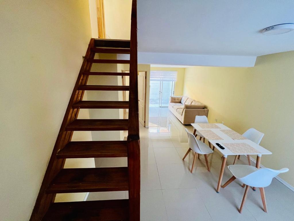 una escalera de madera en una sala de estar con mesa y sillas en Casa 4 habitaciones 1 baño, en Talca