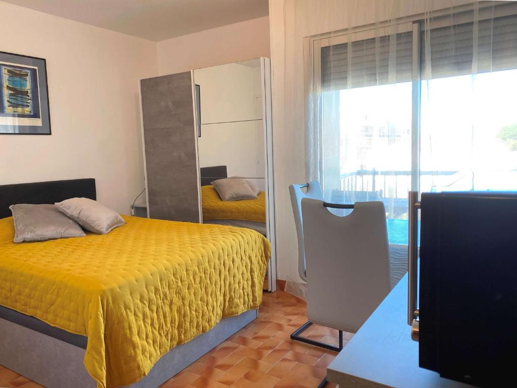 - une chambre avec un lit jaune et un miroir dans l'établissement Coquet Studio Climatisé avec Balcon et Wi-Fi près du Parc à Balaruc-les-Bains - FR-1-553-242, à Balaruc-les-Bains