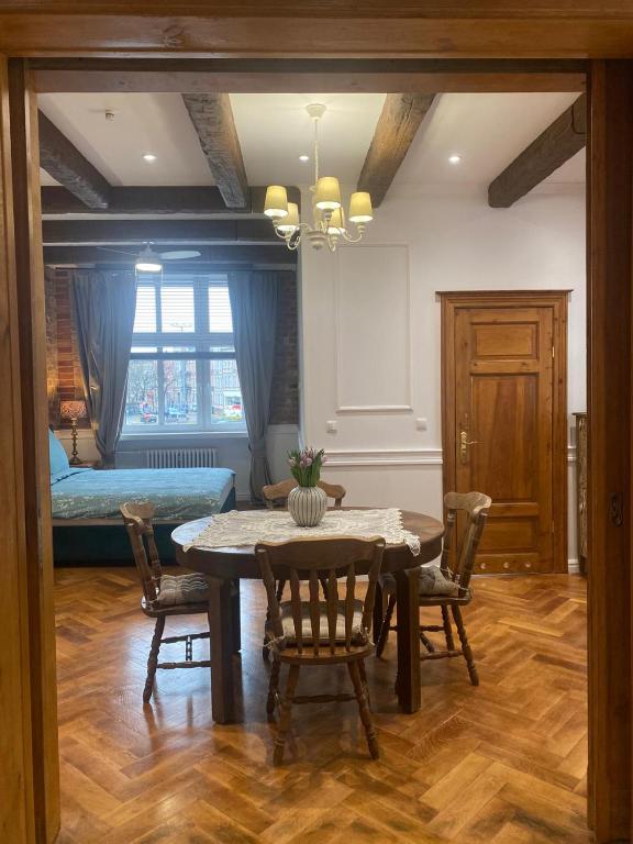 a dining room with a table and chairs and a bed at Apartments PSD - Anny Łajming 1C in Słupsk