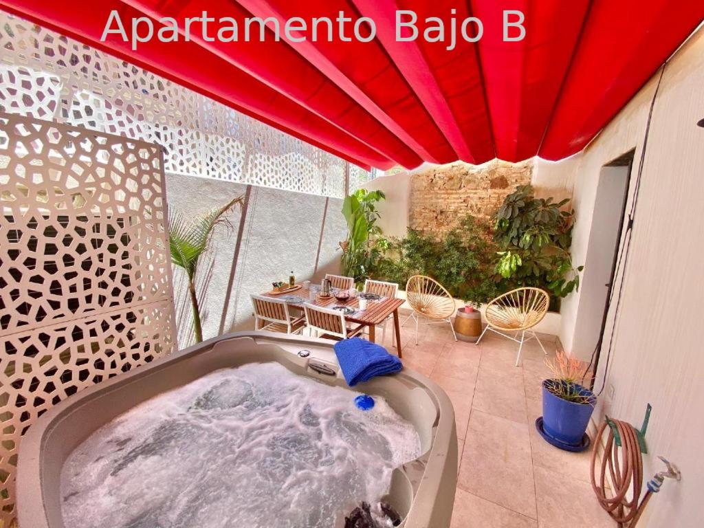 - Balcón con bañera de hidromasaje y sombrilla roja en Apartamentos Simba, en Málaga