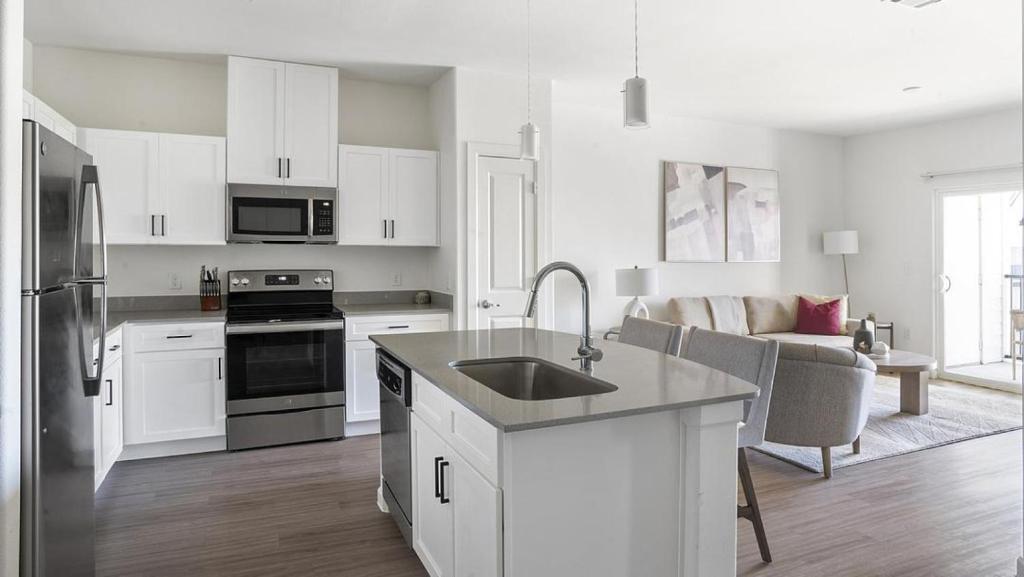 La cuisine blanche est équipée d'un évier et d'un réfrigérateur. dans l'établissement Landing Modern Apartment with Amazing Amenities (ID1377X491), à Pflugerville