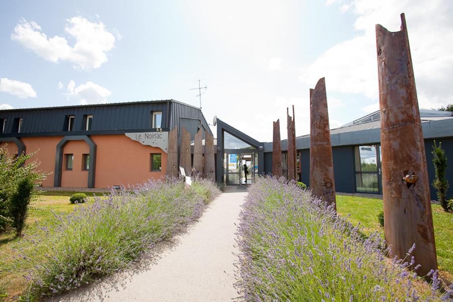 un sentiero che conduce a una casa con un edificio di Le Noirlac a Saint-Amand-Mont-Rond