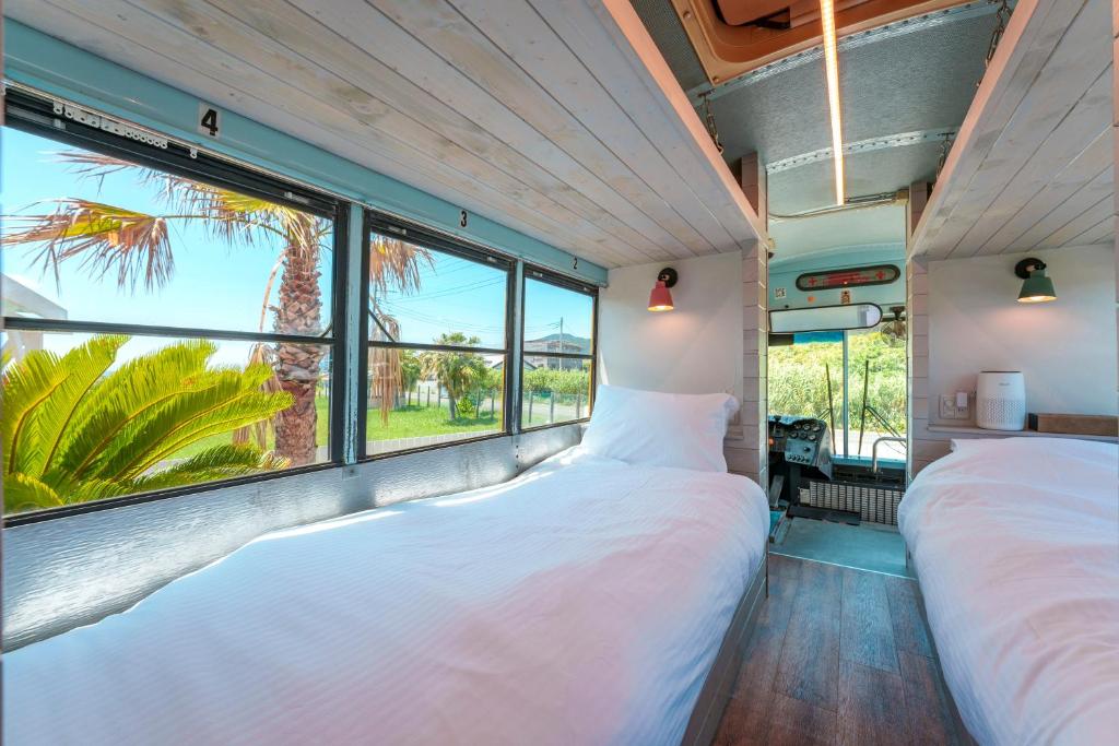 two beds in a room with large windows at Hotel Ocean BUS Shirahama in Shioura