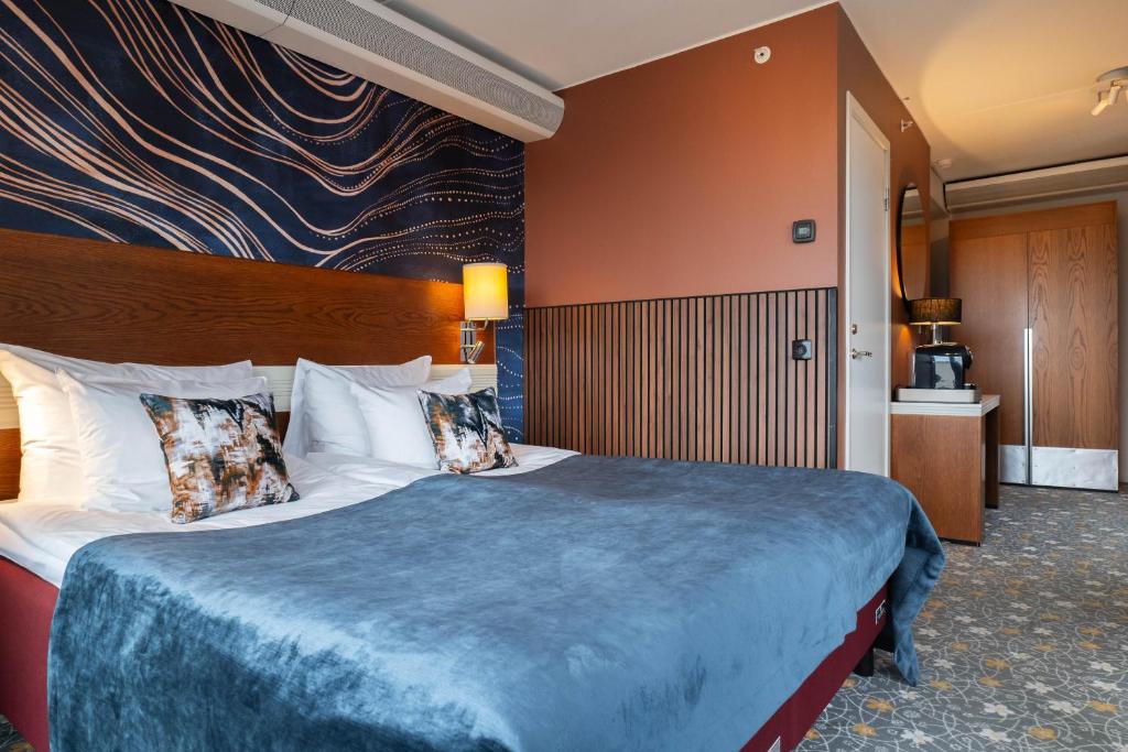 a hotel room with a large bed with a blue blanket at ProfilHotels Opera in Gothenburg