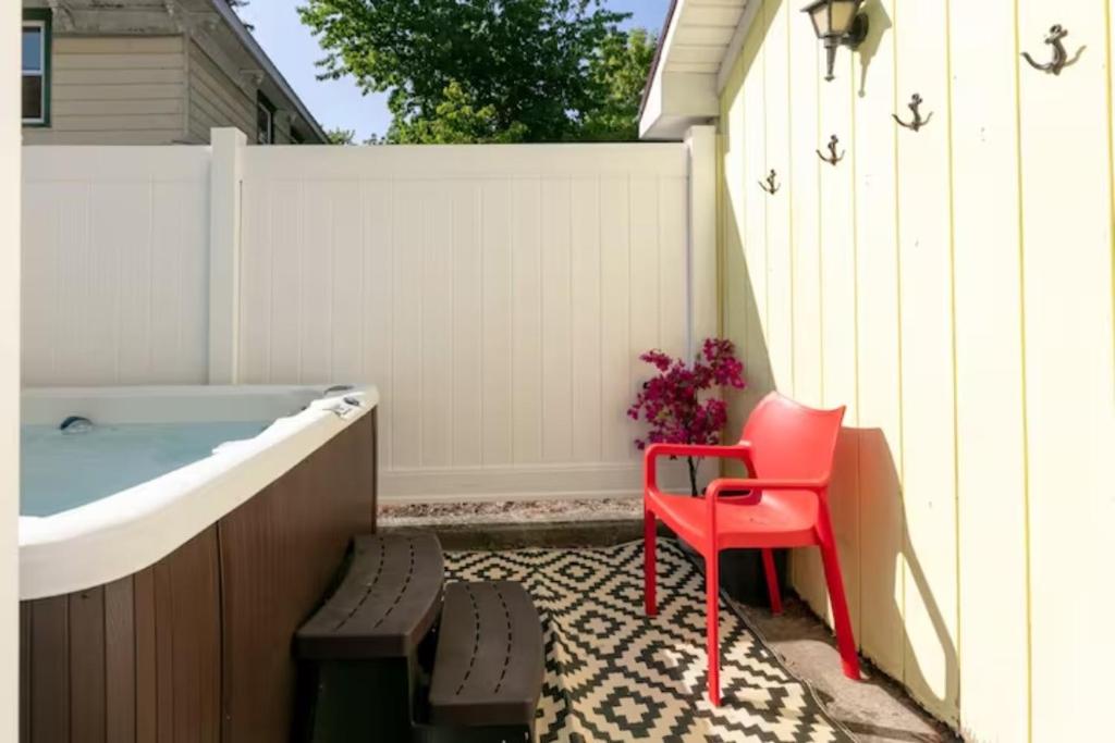 una sedia rossa seduta accanto a una vasca da bagno di Home In The Heart Of Watkins Glen With Hot Tub And Game Rm a Watkins Glen