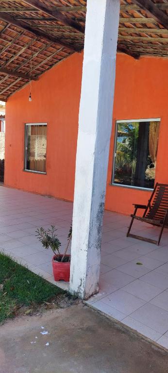 een oranje gebouw met een witte zuil en een potplant bij Paraíso a Beira Mar in Praia Da Caueira