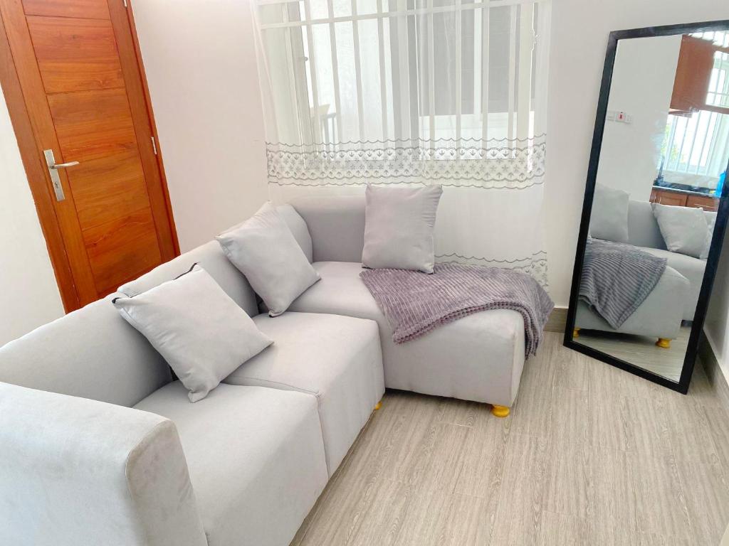 a living room with a white couch and a mirror at LuckySmallie 1-Bed Apartment in Goba Dar es Salaam in Dar es Salaam