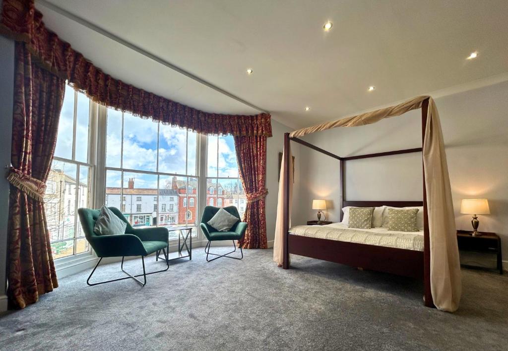 um quarto com uma cama de dossel e 2 cadeiras em The Windmill Hotel em Lincolnshire