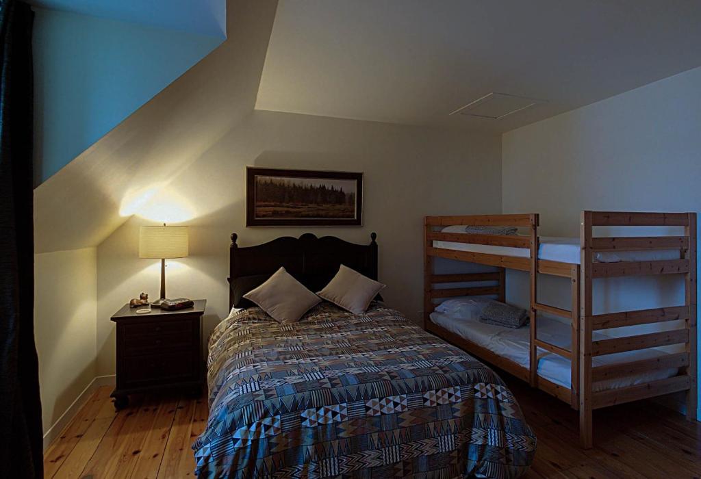 a bedroom with a bed and two bunk beds at Chalet des bouleaux in Nominingue