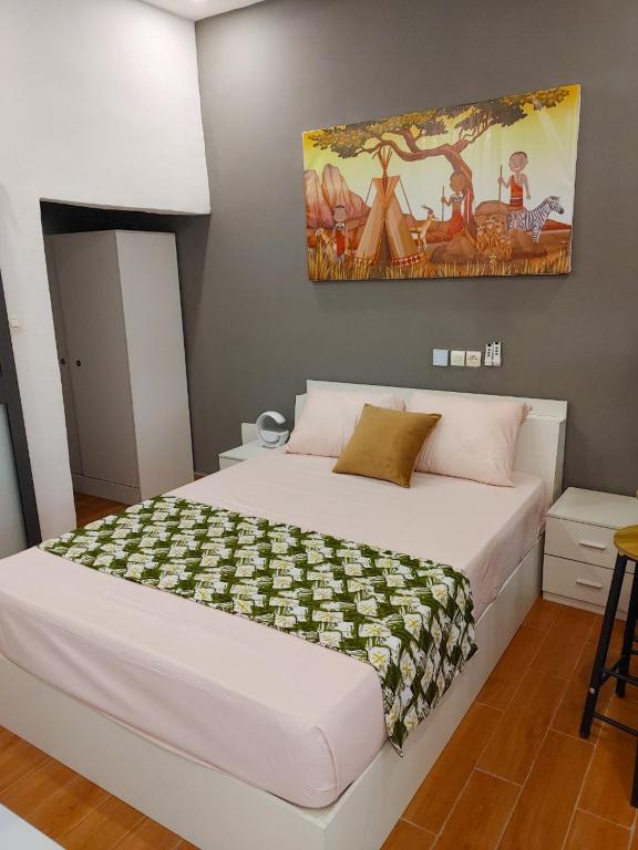 a bedroom with a large white bed with a painting on the wall at LES 9 PLURIELLES - Studio 5 in Palimé