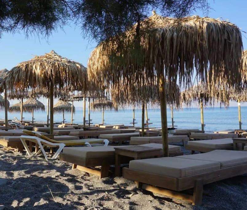 een groep stoelen en rieten parasols op het strand bij Creta Irini's Rooms3 in Tympáki