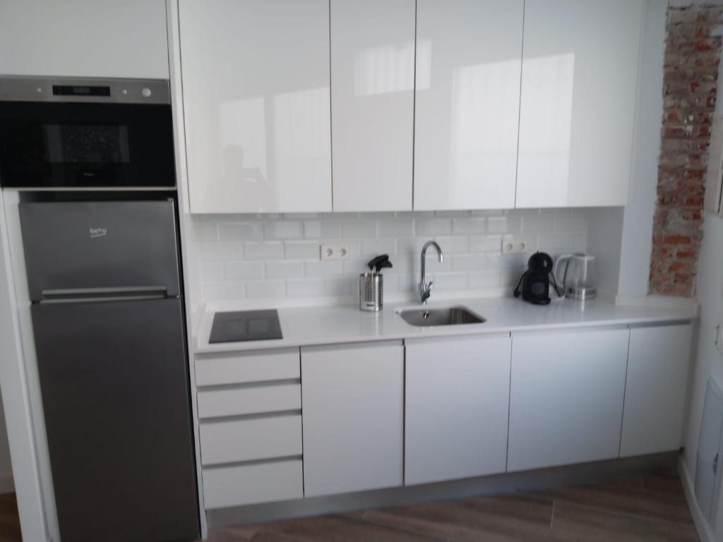 cocina con armarios blancos y nevera negra en Francos Rodriguez2 Apartments, en Madrid