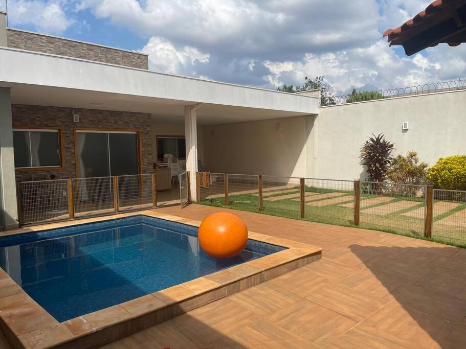 een zwembad met een sinaasappel in het midden bij Pousada e Edícula in Jabuticabal