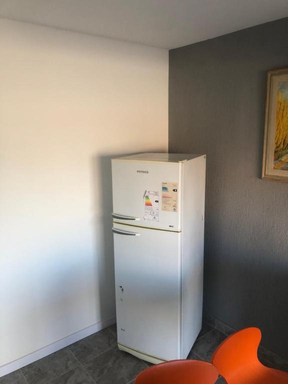 Casa de Playa في بلاليا أونيون: ثلاجة بيضاء في غرفة بها كرسي برتقالي