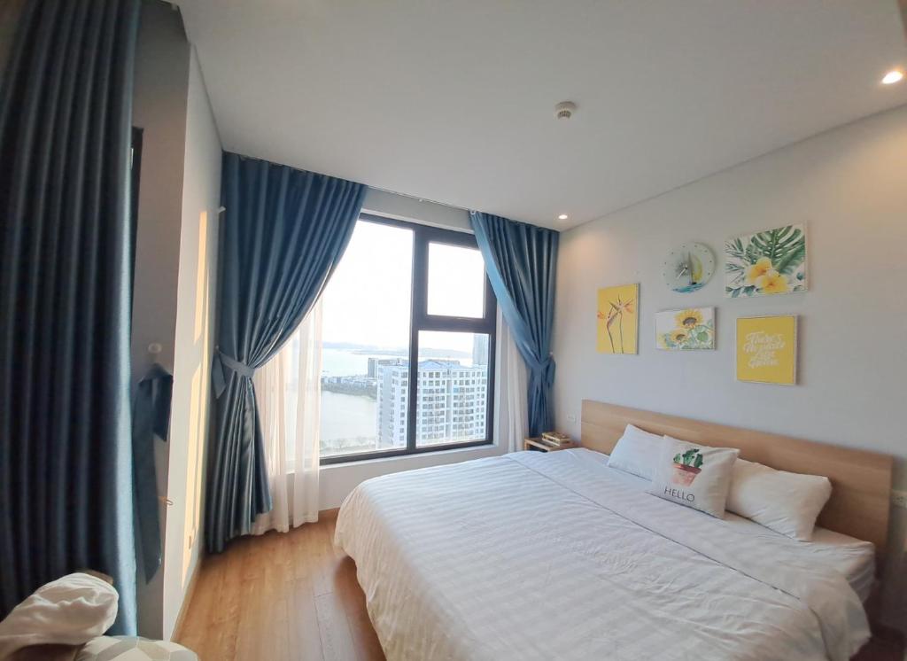 a bedroom with a large bed and a large window at Mon Cherry Apartment -Greenbay Garden Ha Long in Ha Long