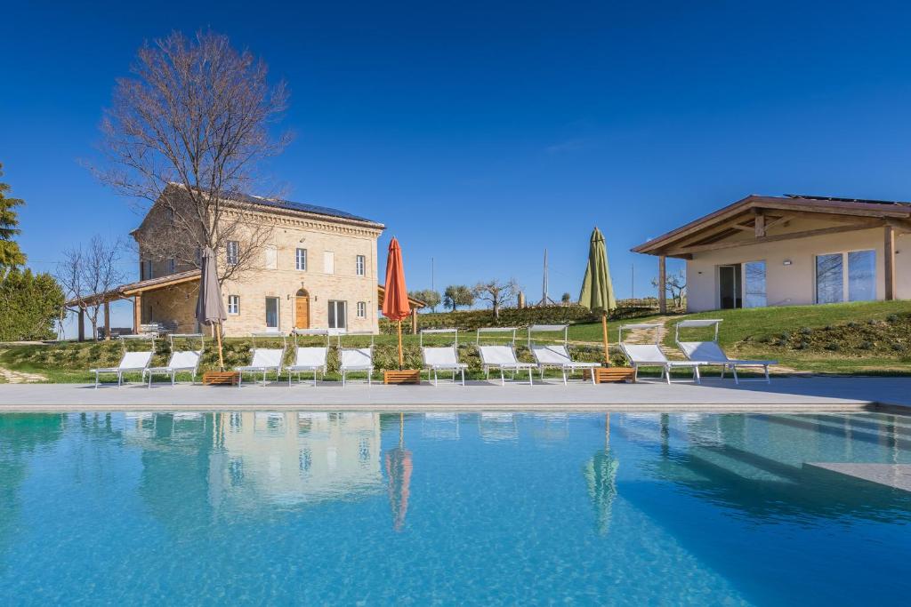 una piscina frente a una casa con sillas y sombrillas en Villa Margherita en Francavilla dʼEte