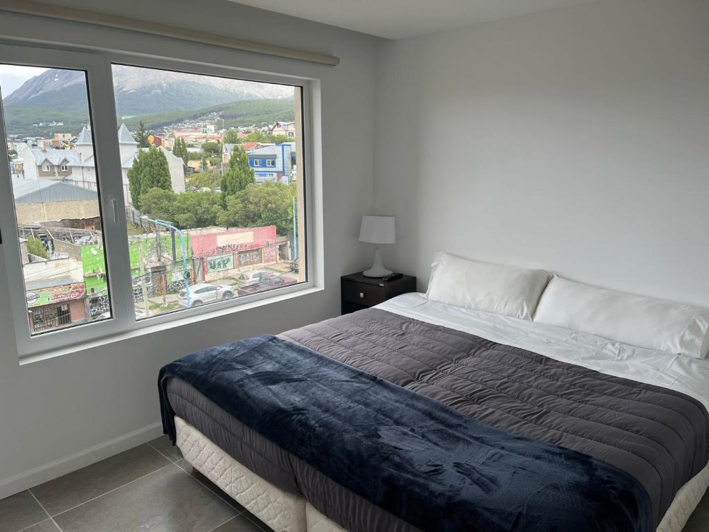 - une chambre avec un lit et une grande fenêtre dans l'établissement Ushuaia Center Apartament Suit, à Ushuaia