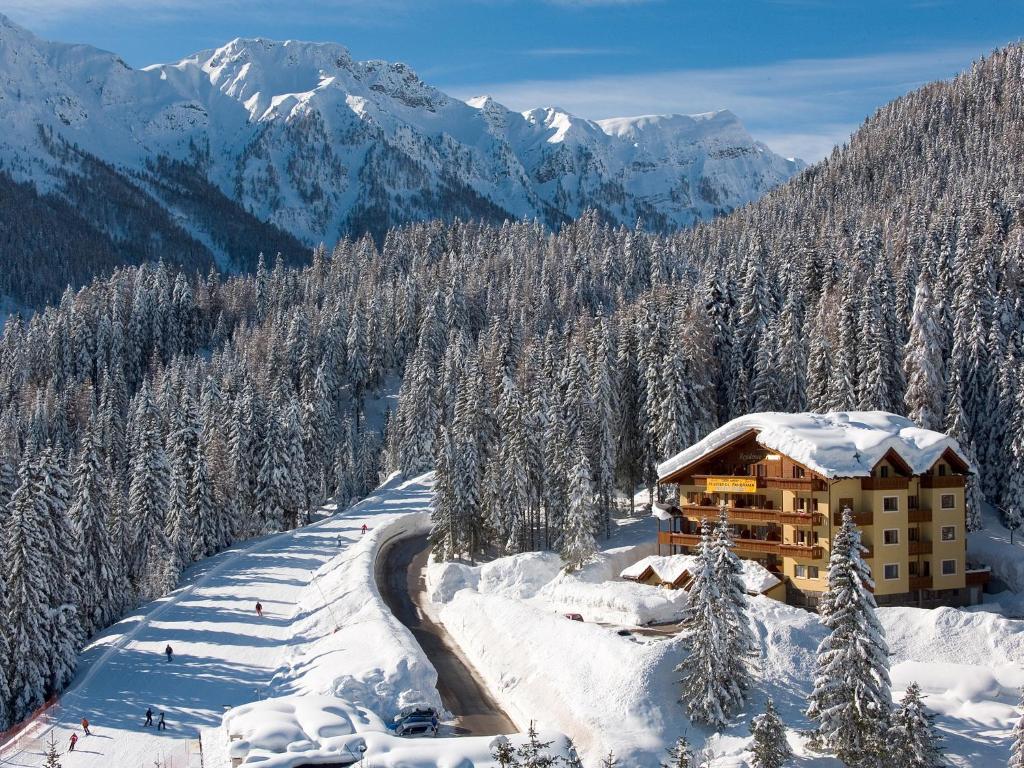 a ski lodge in the mountains with snow covered trees at Residence Panorama in Falcade