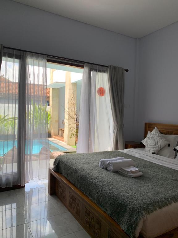a bedroom with a large bed and a large window at Chua Guest house Canggu in Canggu