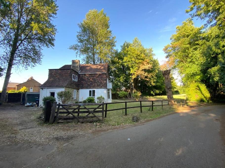 a white house with a fence next to a road at 3 bed house near Gatwick and Redhill in Bletchingley