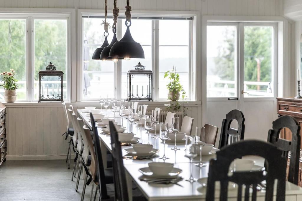 een lange eetkamer met een lange tafel en stoelen bij Historic lakeside villa - ski, boat, relax in nature in Sunnansjö