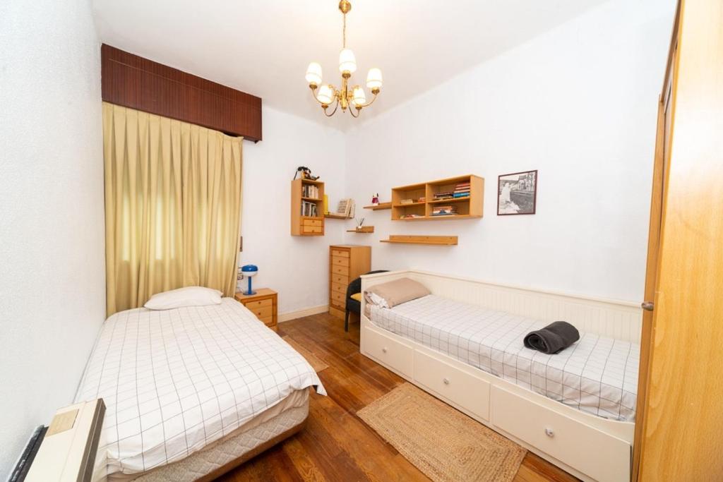 a bedroom with two beds and a chandelier at Soul Etxia in Bermeo