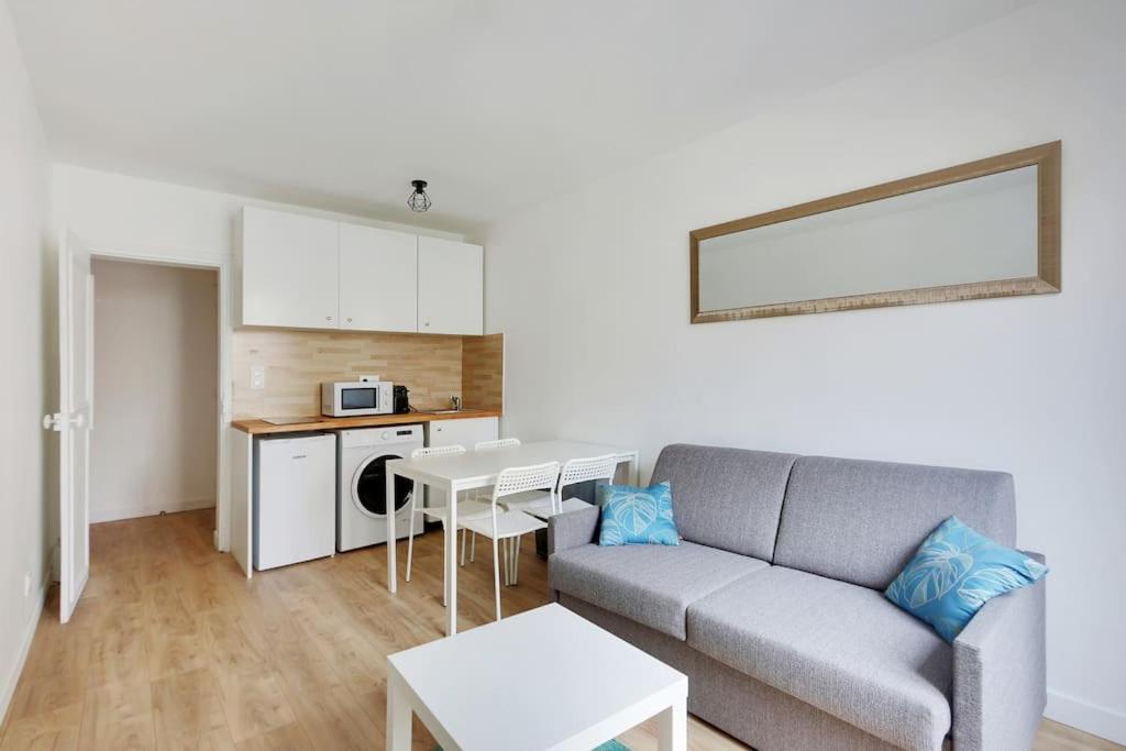 a living room with a couch and a kitchen at Appartement Suite aux Portes de Paris in Clichy
