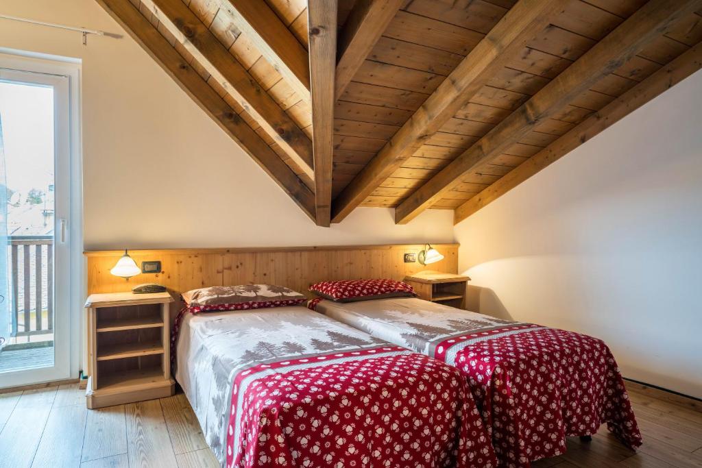 um quarto com uma cama grande com lençóis vermelhos e brancos em Giongo Residence Aparthotel 202 em Lavarone