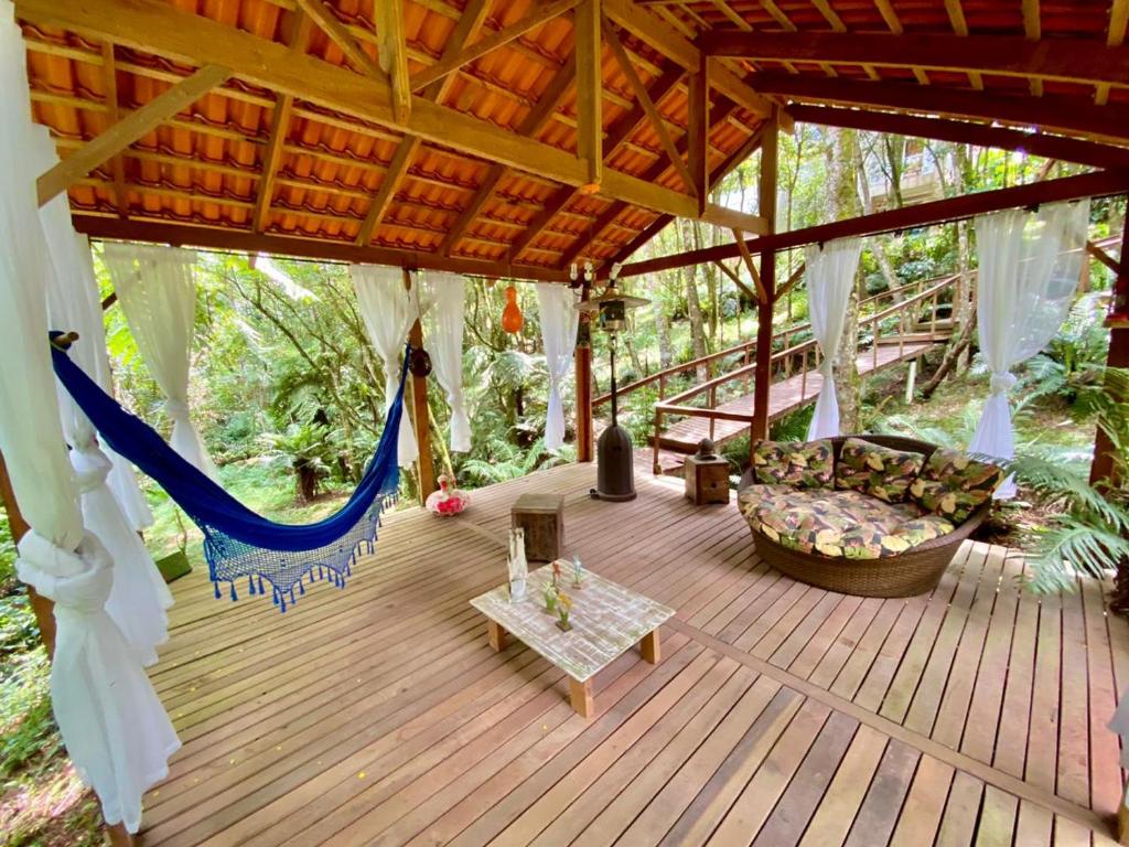 a porch with a couch and a hammock on a deck at Chácara Flor de Iris in Piraquara