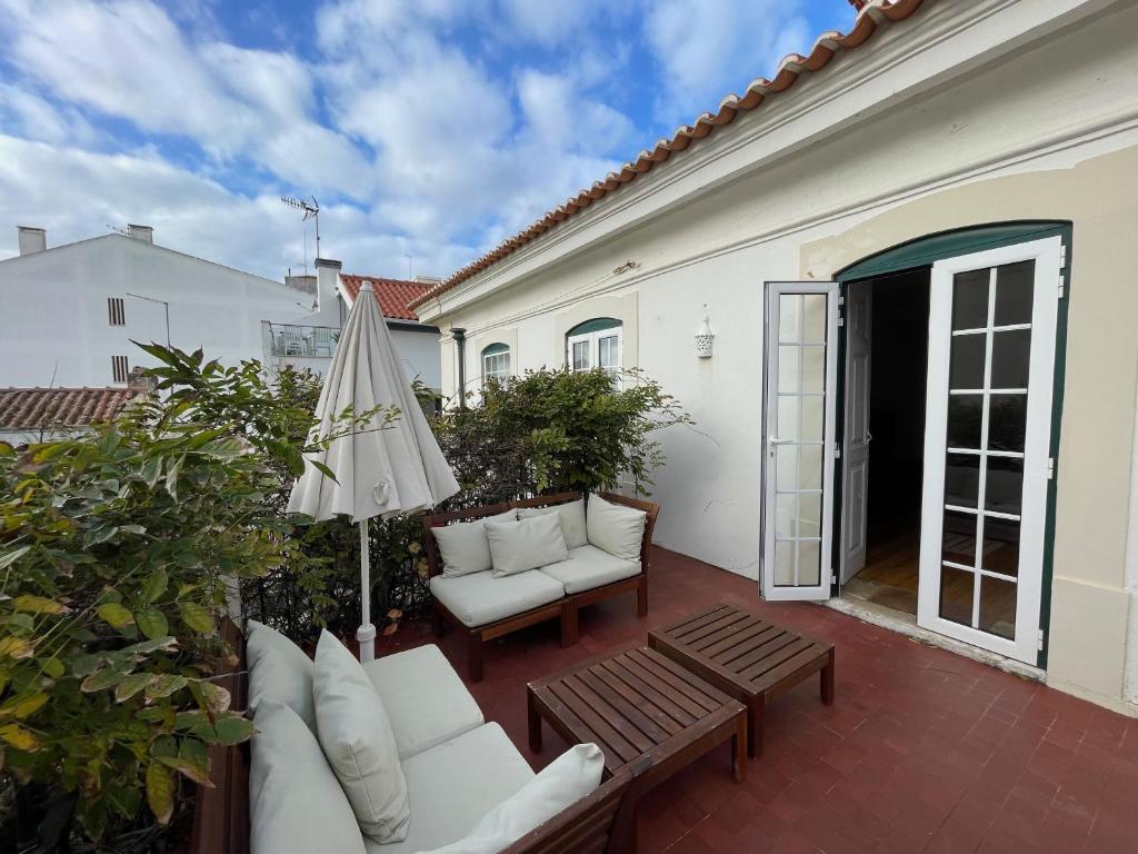 um pátio com dois sofás brancos e um guarda-chuva em Charming beach house em São Martinho do Porto