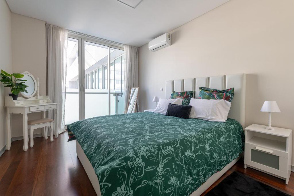 een slaapkamer met een groot bed met een groene sprei bij Funchal Plaza in Funchal