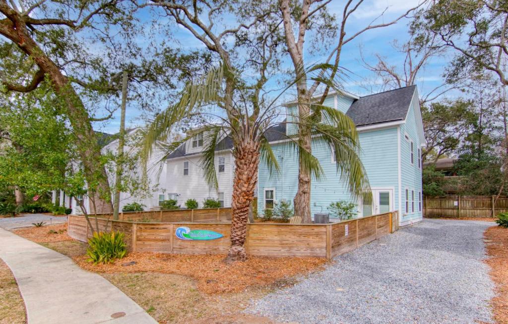 a house with a fence and a palm tree at Ride The Wave 5 min to Beach 7 min to Dtwn in Charleston