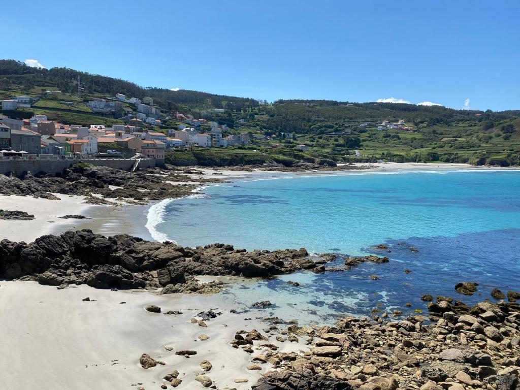 uma praia com pedras e o oceano e casas em Casa de playa TABI Caión- A Coruña (VUT-CO-000899) em Cayón