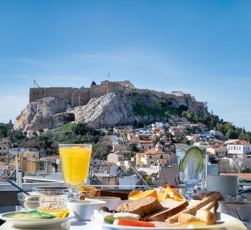 a table with bread and orange juice and a view ofhens at Hotel Adonis Athens in Athens