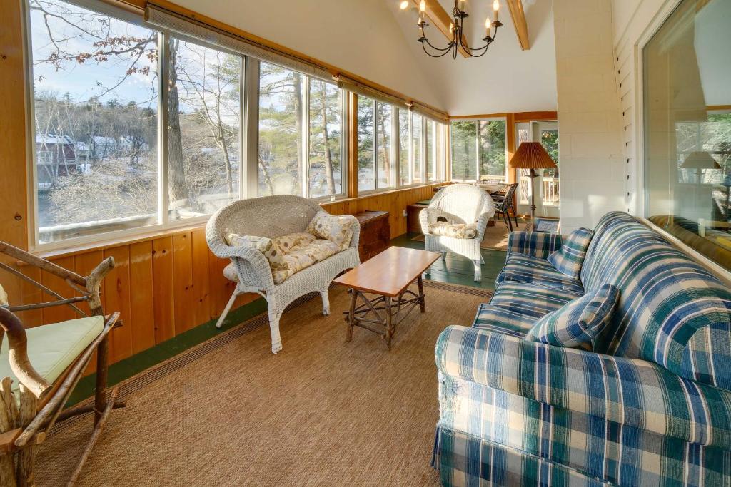 uma sala de estar com um sofá, cadeiras e janelas em Lakefront Bradford Cottage with Dock, Near Skiing! em Bradford