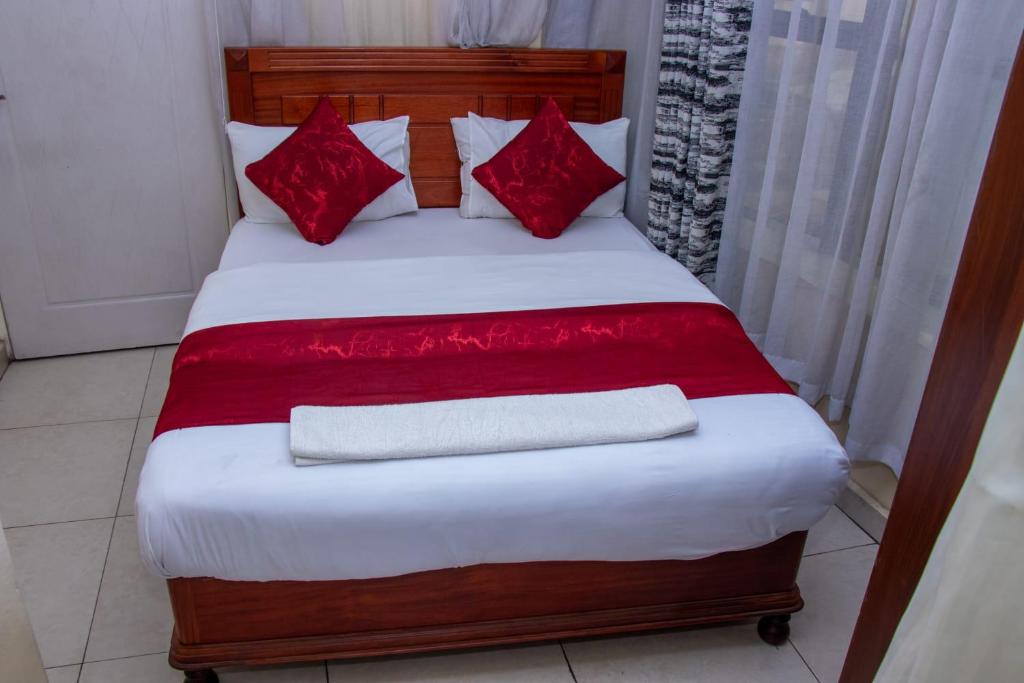 een bed met rode kussens en een rode deken bij Epitome Times Hotel in Nairobi