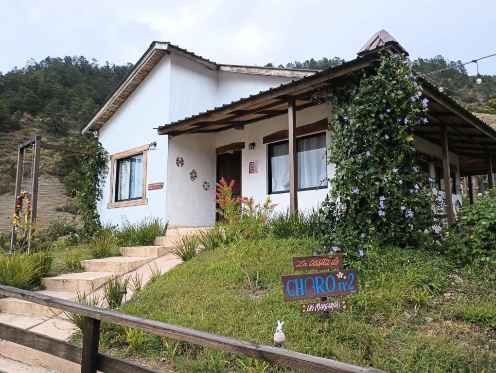 Uma casa branca com um cartaz à frente. em La Casita de Charo 2 em Constanza